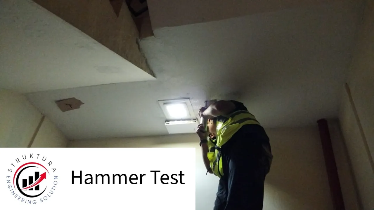 Technician performing a Hammer Test on an elevated concrete element with work lighting