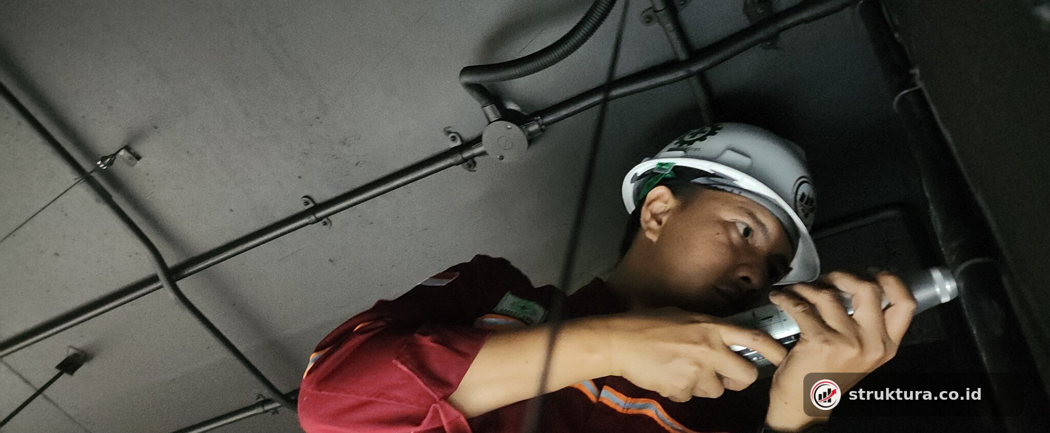 Teknisi menggunakan rebound hammer pada elemen beton di area dengan akses terbatas