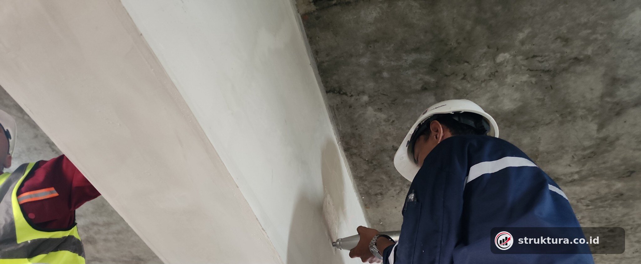 Teknisi menguji sisi balok beton menggunakan rebound hammer
