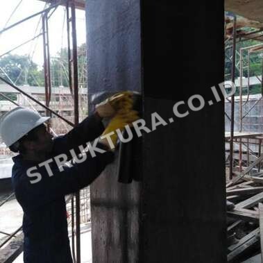 Aplikator meratakan lembaran FRP pada permukaan kolom beton