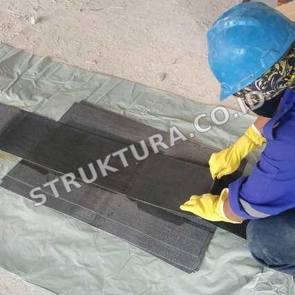 Aplikator menyiapkan lembaran carbon fiber sebelum pemasangan FRP
