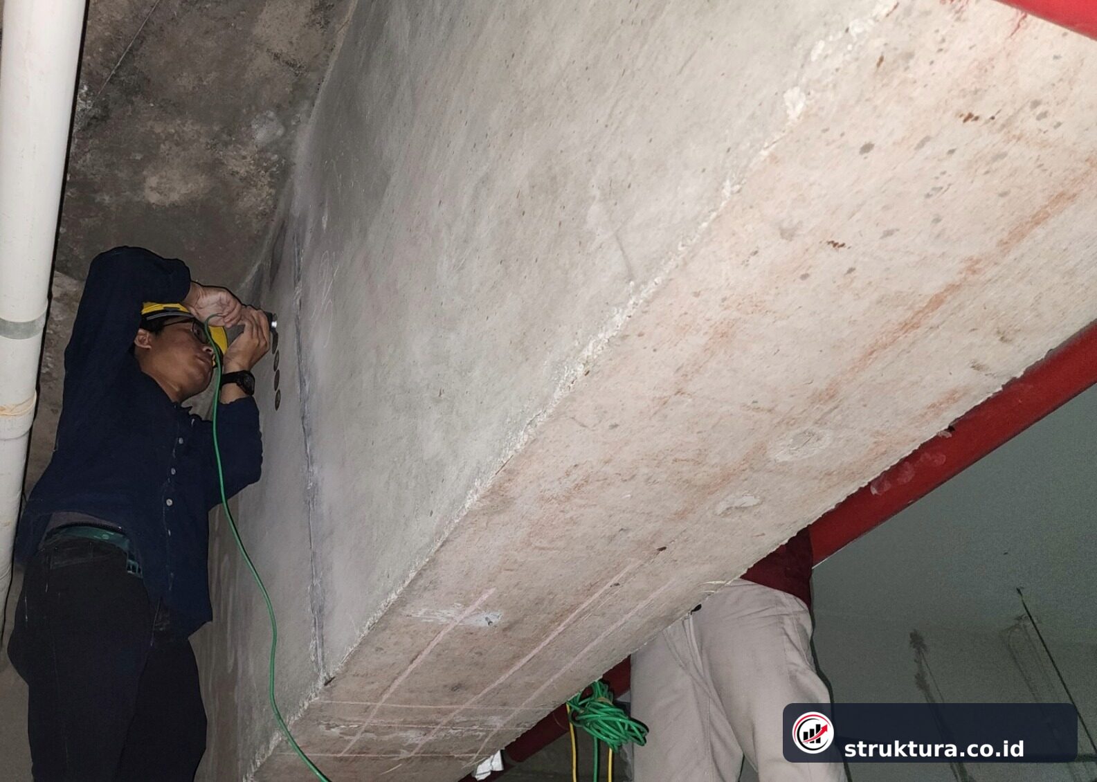 Dua teknisi mengoordinasikan transmitter dan receiver UPV pada dua sisi elemen beton
