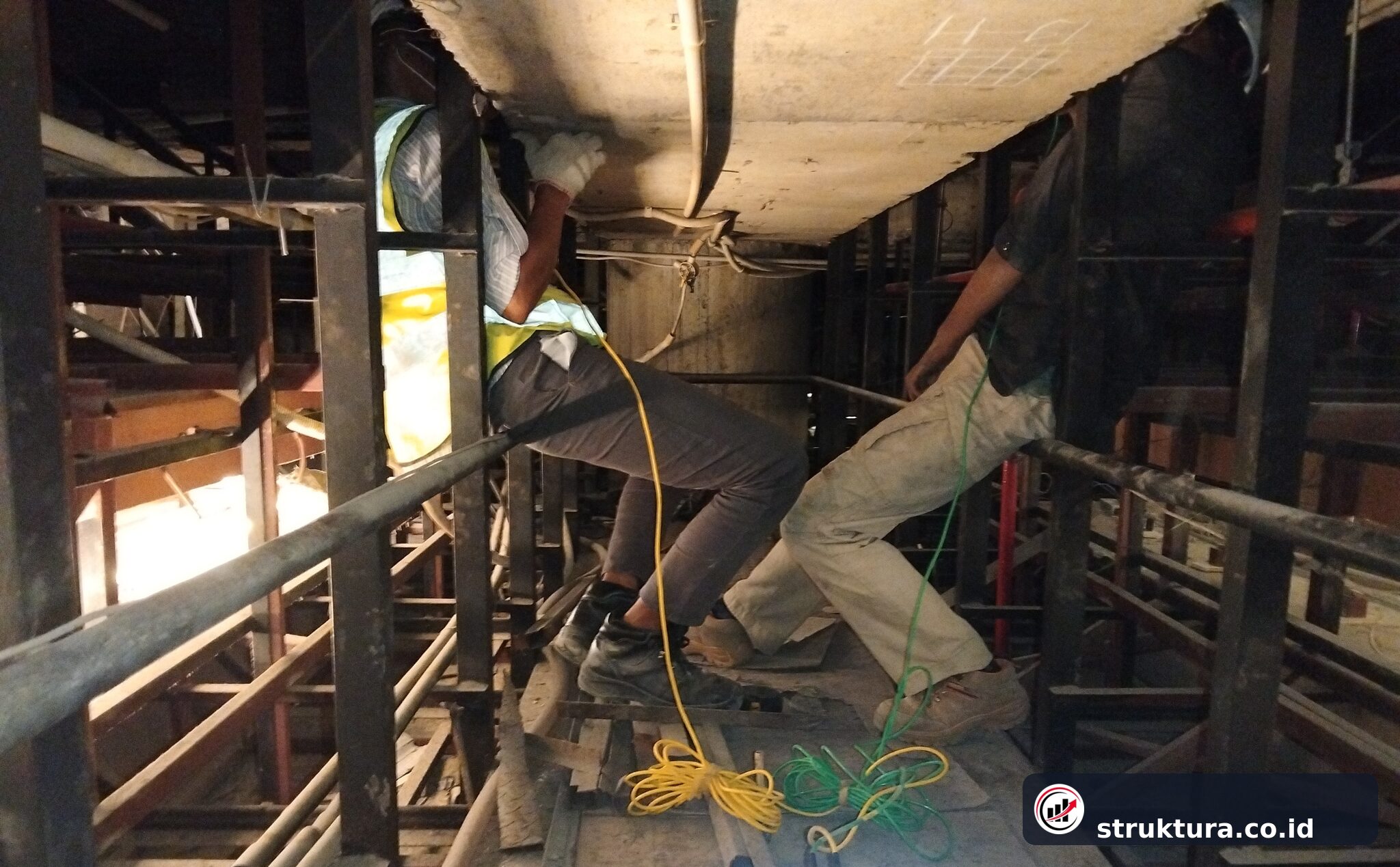 Dua teknisi melakukan UPV Test pada elemen beton di area dengan ruang kerja terbatas