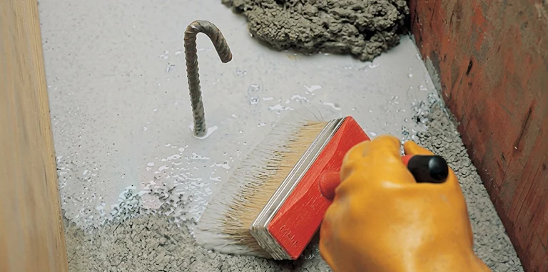 Aplikasi material dengan kuas pada permukaan beton