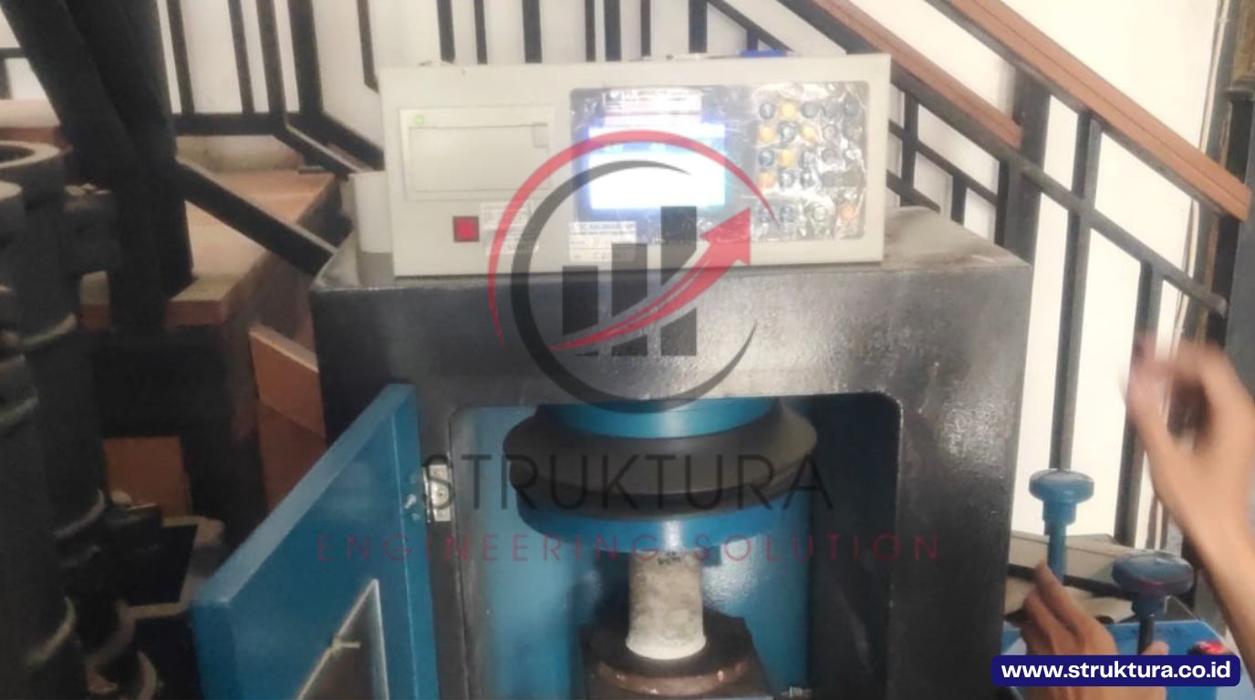 Proses pembebanan sampel inti beton pada mesin uji tekan untuk verifikasi hasil core drill